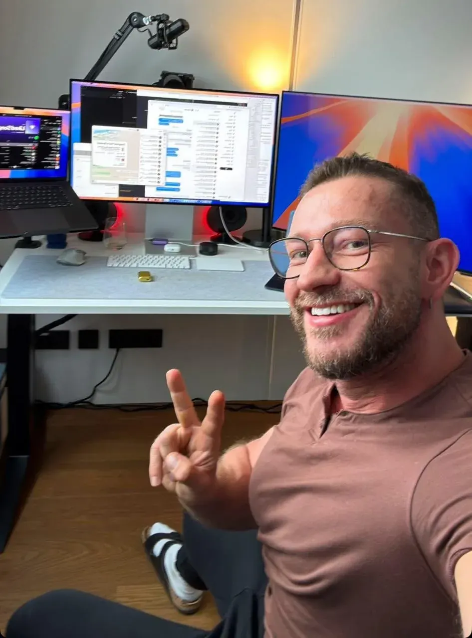 Man taking a selfie in a home office with dual monitors, a laptop and desk accessories for share structure advisory content Man taking a selfie in a home office with dual monitors, a laptop and desk accessories for share structure advisory content